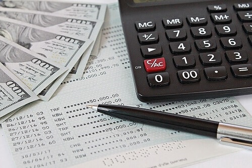 How Outsourcing Accounting Saves You Money by Sensible Services ABC. Image with dollars, calculator, pen, and financial statement.