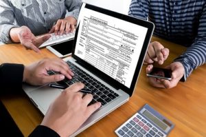 3 Simple Tips for Stress-free Tax Preparation in 2023 | Sensible Services ABC in Hammond, LA. Closeup image of a tax accountant working on his laptop as he helps two individuals with their tax preparation and planning.
