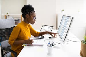 Customized Accounting Services | Sensible Services ABC. Image of african american professional woman going over numbers on a spreadsheet on desktop computer.