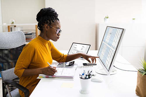Customized Accounting Services | Sensible Services ABC. Image of african american professional woman going over numbers on a spreadsheet on desktop computer.